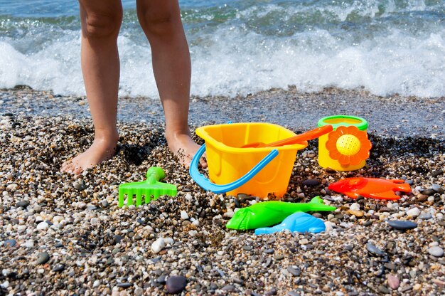 Kinderbeine und Spielzeug am Strand