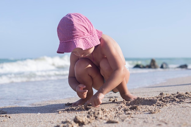 Kinderblondes Mädchen wird mit Sand am Strand gespielt