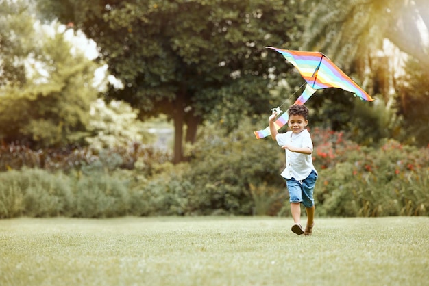 Kinderdrachen und Gras beim Laufen für Wind, um Luft und Himmel zu heben, während sie Spaß und Freude im Freien spielen Junge Spielzeug und Rasen im Garten Hinterhof oder Park im Sonnenschein Sommer und Natur beim Spielen