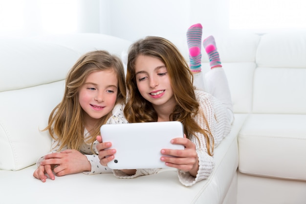 Kinderfreunde scherzen die Mädchen, die zusammen mit Tabletten-PC spielen