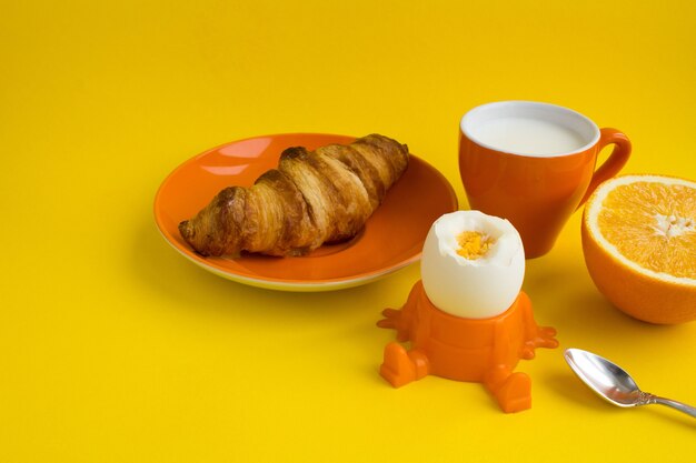 Kinderfrühstück gekochtes Ei, Croissant, Milch und Orange