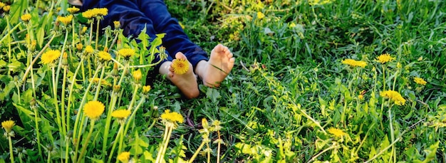 Kinderfüße auf dem Hintergrund von Löwenzahn-Natur