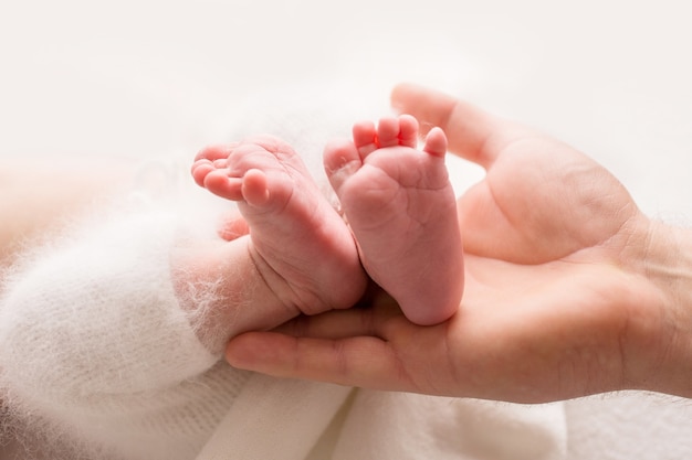 Kinderfüße in den Händen von Mutter und Vater. Mutter, Vater und Kind. Glückliches Familienkonzept. Foto in hoher Qualität