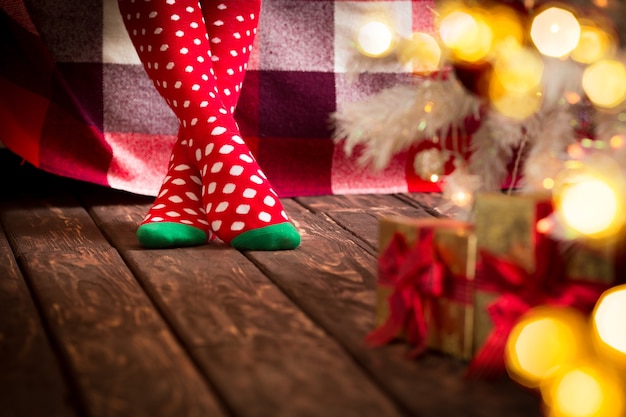 Kinderfüße in Weihnachtssocken in der Nähe von Weihnachtsbaum