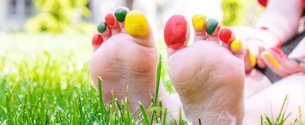 Foto kinderfüße mit einem farbmuster lächeln auf dem grünen gras. selektiver fokus. natur.