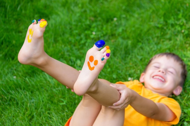 Kinderfüße mit einem Muster aus Farben lächeln auf dem grünen Gras Selektiver Fokus