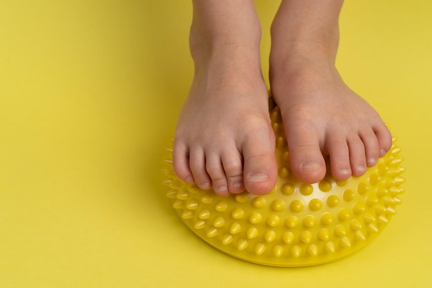 Kinderfüße mit gelbem Balancer auf hellgelbem Hintergrund Behandlung und Vorbeugung von Flat