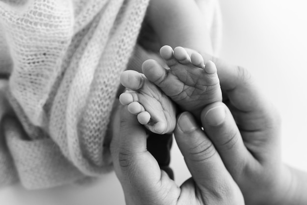 Kinderfuß in den Händen der Mutter Vater Eltern Füße eines winzigen Neugeborenen Nahaufnahme kleine Babybeine Mutter und ihr Kind Glückliches Familienkonzept Schwarz-Weiß-Bild der Mutterschaft Stockfoto