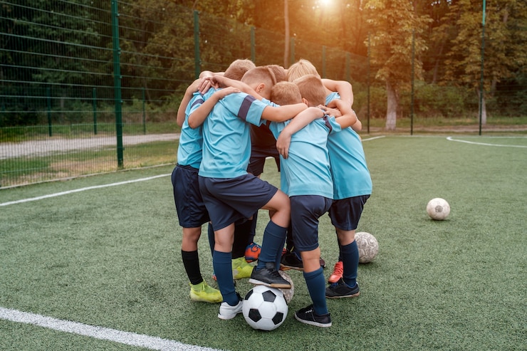 Foto kinderfußballmannschaft und trainer umarmen sich vor dem spiel auf dem fußballplatz
