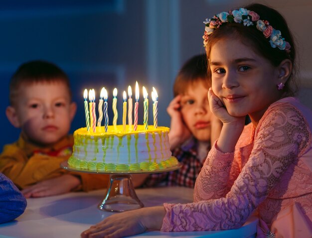 Kindergeburtstag. Kinder nahe einem Geburtstagskuchen mit Kerzen.