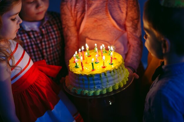 Kindergeburtstag. Kinder nahe einem Geburtstagskuchen mit Kerzen.