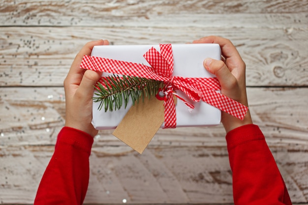 Kinderhände, die Geschenk-Weihnachtsbox halten. Ansicht von oben.