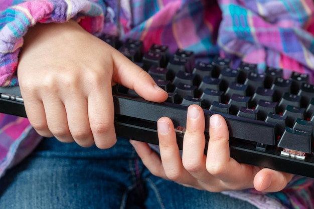 Foto kinderhände halten eine schwarze tastatur in ihren händen