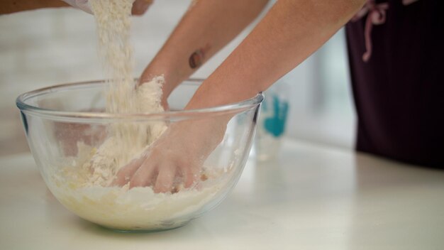 Kinderhände kochen Teig. Mädchenhand bereitet Teig zu. Tochter bereitet Kuchen zu