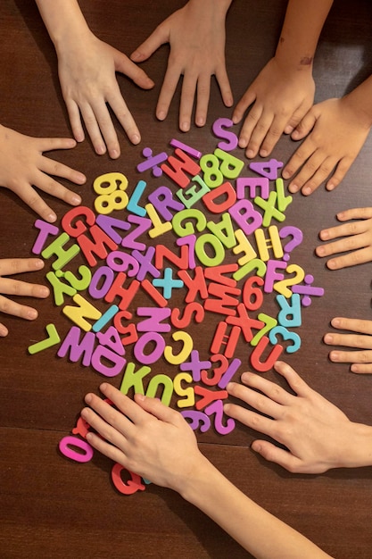 Foto kinderhände mit bunten plastikzahlen auf dem braunen tisch