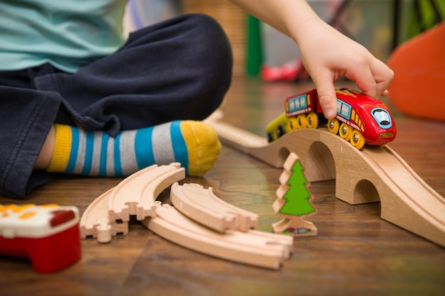 Kinderhände mit Spielzeugeisenbahn und Eisenbahn in seinem Zimmer hautnah