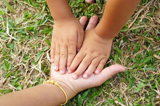 Kinderhände und Mutterhände berühren das Gras und die Erde