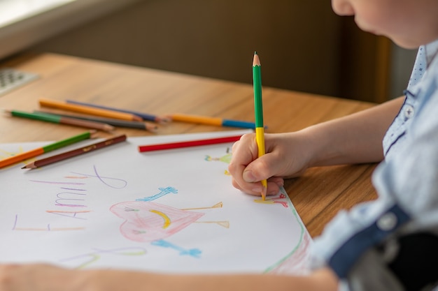 Kinderhand, die einen Buntstift hält, zeichnet ein Bild der Liebe für die Familie