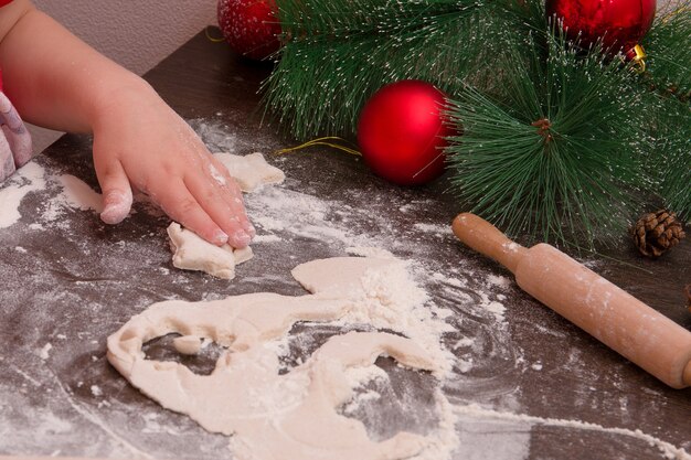 Kinderhand formen Kekse, Neujahr, Weihnachtshintergrund, Kopierplatz, Keks in Form eines Sterns, dunkler Holztisch