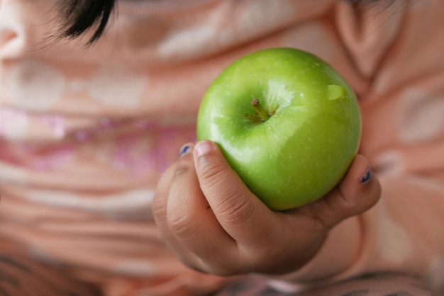 Kinderhand hält einen grünen Apfel