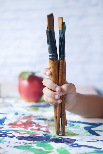 Kinderhand halten Kunstpinsel auf einem Papier