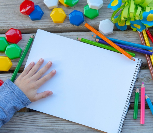 Kinderhand mit leeren weißen Papierblattmodellzeichenwerkzeugen und Keksen