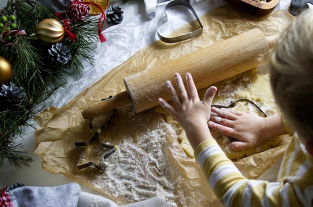 Kinderhand schnitzt Figuren für Weihnachtsplätzchen aus dem Teig