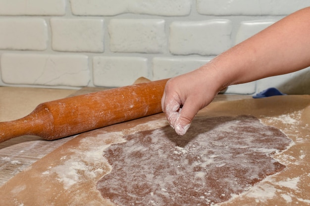 Kinderhand streut Mehl auf den Teig Bildet Mehl Holztisch