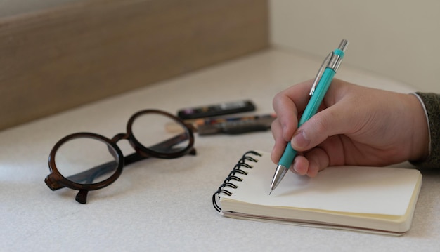 Foto kinderhand verwenden mechanischen bleistift, der auf papiernotizbuch schreibt