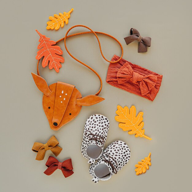 Kinderhandtaschenform aus niedlichen Rehen, Babystiefeln und Herbstblättern. Set von modischen Kinderaccessoires für den Herbst. Flache Lage, Ansicht von oben