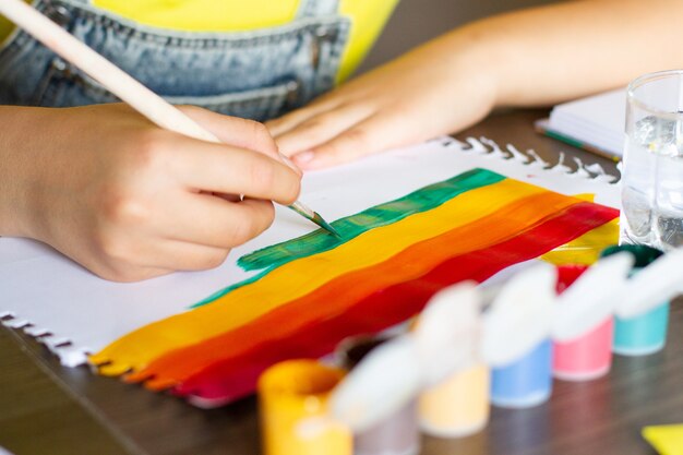 Kinderhandzeichnung, die bunten Regenbogen malt