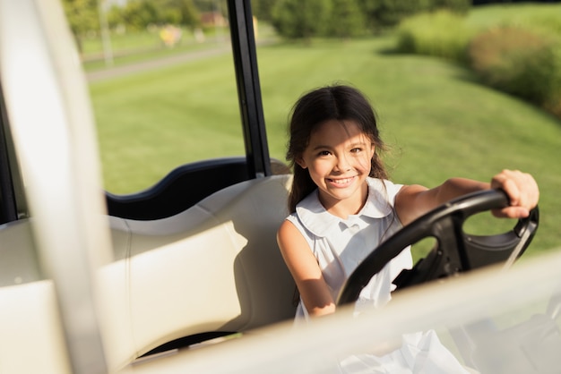 Kinderhobby-junges Mädchen, das im Luxusgolfwagen sitzt.