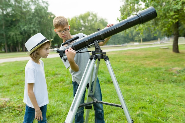 Kinderjugendliche im Park, der durch ein Teleskop schaut