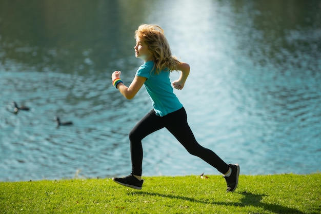 Kinderjunge, der im Park im Freien joggt Sportliches Kind, das in der Natur läuft Aktiver gesunder Kinderjungenläufer, der im Freien joggt