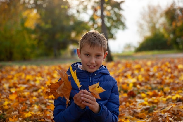 Kinderjunge, der in den Herbstpark geht Der Herbst verlässt Kinderkonzept