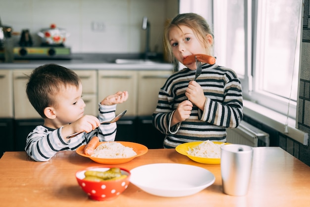 Kinderjunge, der in der Küchenwurst und in den Nudeln isst