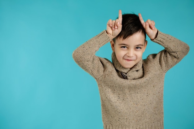 Kinderjunge, der lustige Gesten mit dem Finger über dem Kopf als Stierhörner macht