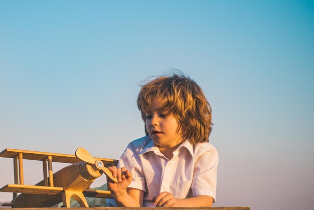 Kinderjunge, der mit hölzernem Spielzeugflugzeug spielt, träumt davon, Pilot zu werden Kinderträume Kinderpilotflieger mit Holzflugzeug