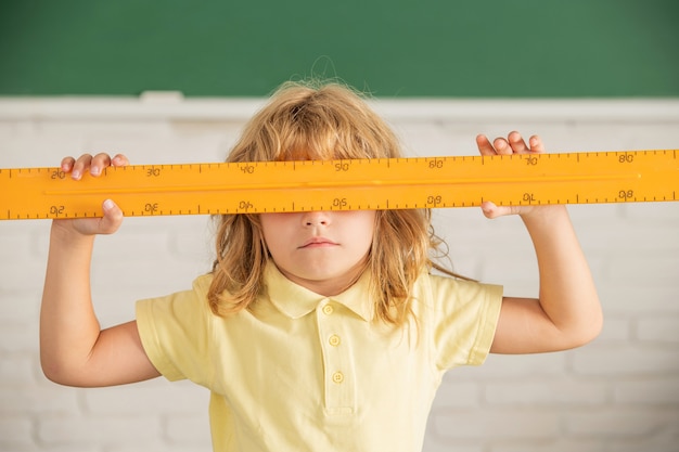 Kinderjunge in der Schule, die Mathelinealwerkzeug, Schule hält