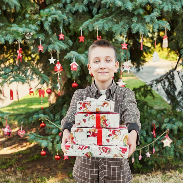 Kinderjunge mit Geschenken nahe einem Weihnachtsbaum