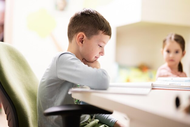 Kinderjunge mit Schwester, die zu Hause lernt und Schulhausaufgaben macht, Fernunterricht, der am Tisch sitzt