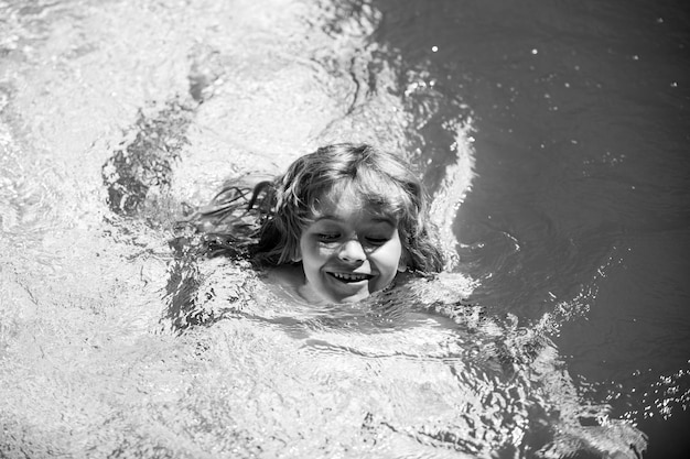 Kinderjunge schwimmen im Schwimmbadwasser Kind spielen im Freien Sommerferien und gesunder Lebensstil