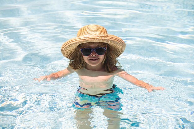 Kinderjunge schwimmt im Schwimmbad süßer Junge im Wasser, der mit Wasser spielt