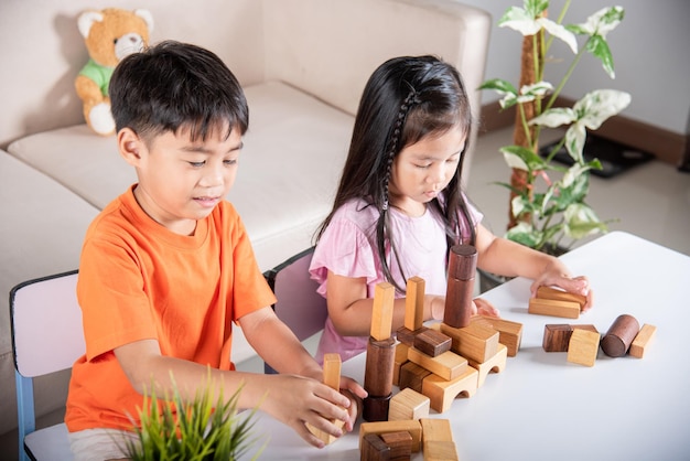 Kinderjunge und -mädchen, die mit Konstruktorholzblockgebäude spielen