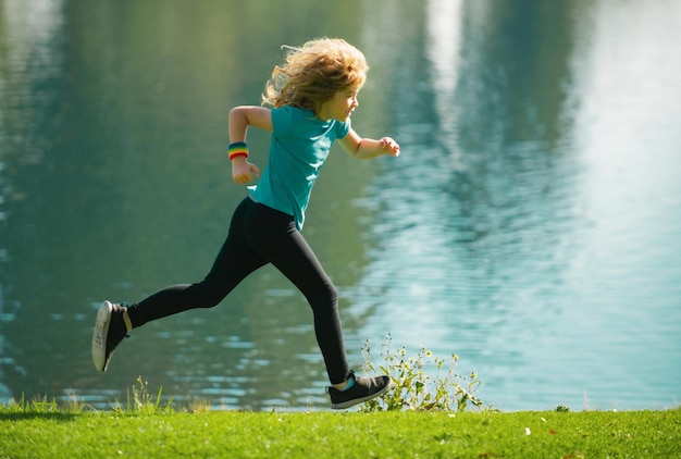 Kinderjungenläufer, die im Park laufen Sportliches junges Kind, das joggt und trainiert Joggen im Freien hilft dem Körper t