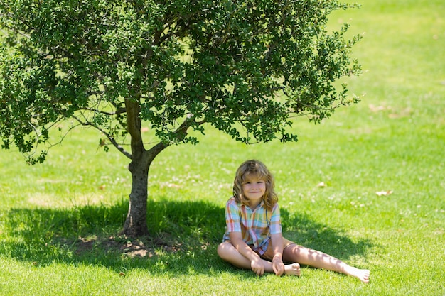 Kinderjungenmädchen, das auf grünen Graskindern ruht, die draußen im Sommer spielen, parken Freiheit und sorglos glücklich