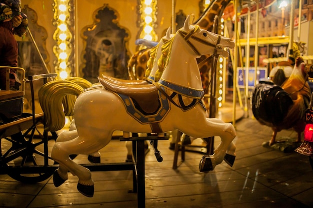 Kinderkarussell in einem Vergnügungspark in der Nachtbeleuchtung ein Spielzeugpferd auf einem Karussell