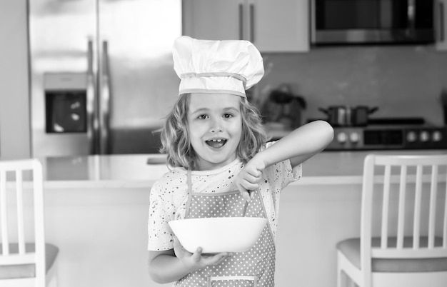 Kinderkoch Koch mit Kochplatte Fun Kinderküche Lustiger kleiner Kinderkoch mit einheitlicher Kochmütze und Schürze gekochtes Essen in der Küche Kinder bereiten Essen zu backen Kekse in der Küche