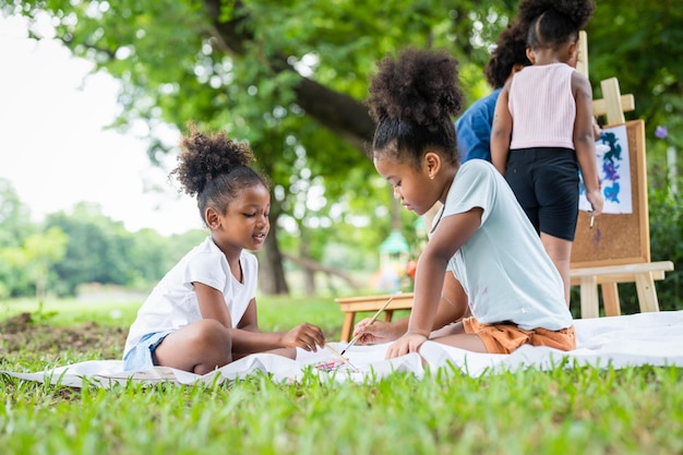 Kinderkünstler afroamerikanische kleine Mädchen zeichnen Bilder und malen Aquarell im Park