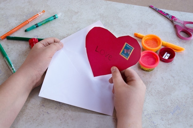 Kinderkunst st valentinstag Thema Handwerk Konzept Kind rotes Herz in Umschlag setzen